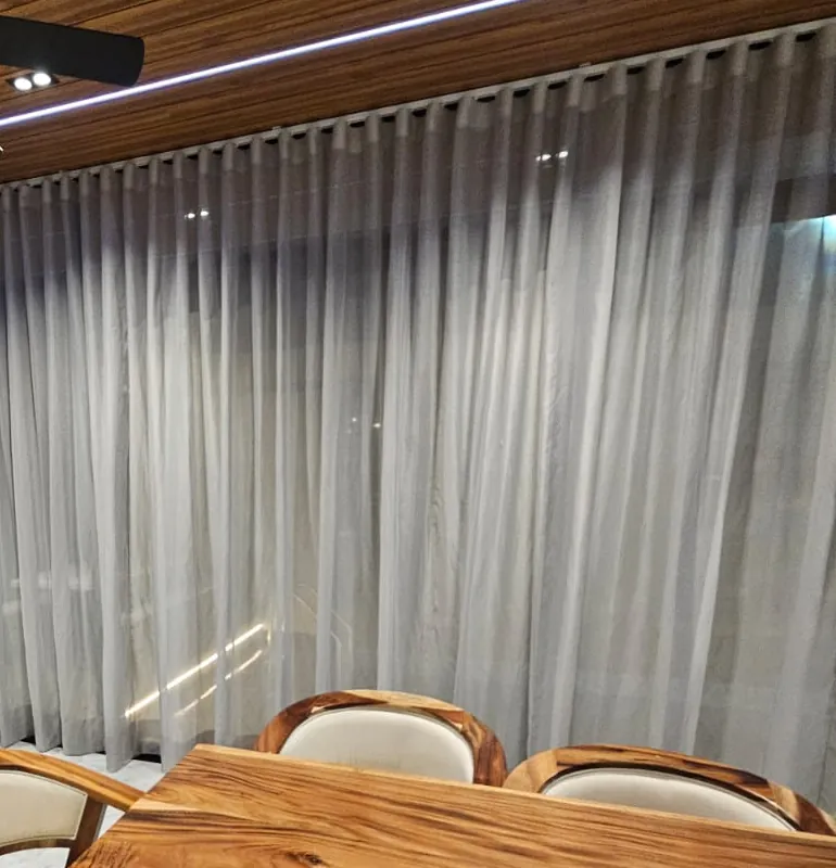 Comedor con cortinas traslúcidas de piso a techo y mesa de madera, instaladas por Moda en Casa
